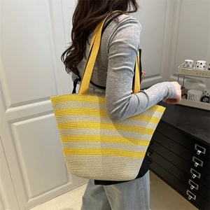 Grand sac de plage tressé à rayures jaunes porté par un mannequin en intérieur