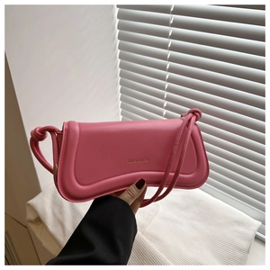 Detail of the pink leather bag showing the golden logo and clean stitching accents