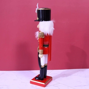 Traditional red wooden nutcracker soldier with white feathers and scimitar on a stand