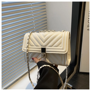 Close-up of white quilted leather crossbody bag with metal chain strap and turn-lock