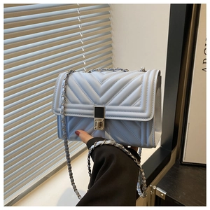 Detail of light blue quilted crossbody bag with silver twist lock and chain strap