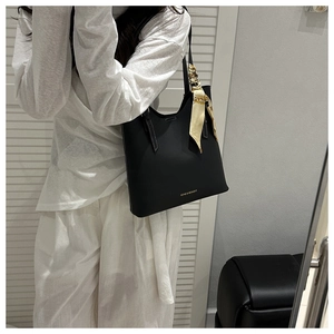 Close-up of black tote bag with white stitching and decorative silk scarf on handle