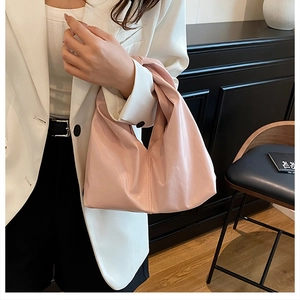 Détail du sac à main rose en cuir souple avec une poignée nouée élégante