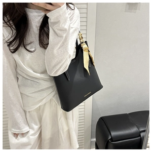 Detail view of black faux leather tote with white stitching and floral silk scarf accessory