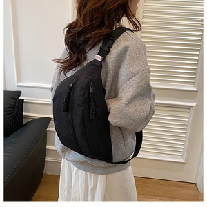 Detail of black nylon chest bag with double vertical zippers and woven pullers