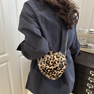 Fashionable leopard print heart-shaped crossbody bag with gold chain strap shown on model