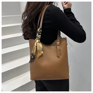 Brown leather tote bag detail with decorative silk scarf and adjustable shoulder straps