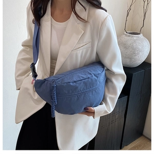 Detail of the blue crescent crossbody bag with waterproof nylon texture and woven zipper pull