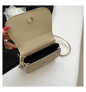 Detail of beige woven saddle bag showing magnetic clasp closure and black inner lining