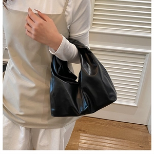 Close-up of black pleated hobo bucket bag showing large capacity and soft leather texture