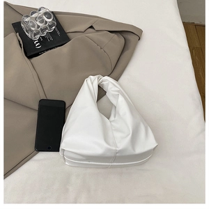 Minimalist white pleated cloud bag with soft leather texture on a neutral fabric background