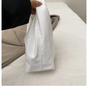 Detail view of the soft white PU leather handbag with side stitching and slouchy structure