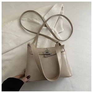 Macro view of cream white leather tote bag featuring a vintage metal turn-lock clasp detail