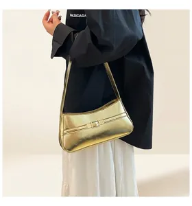 Close-up of gold metallic shoulder bag featuring a modern buckle and textured finish