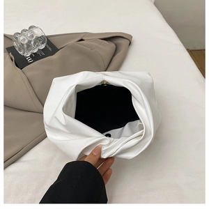 Detailed interior of a white pleated cloud clutch showing the magnetic gold metal clasp