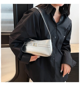 Close-up of metallic silver shoulder bag featuring a sleek gold buckle and minimalist strap