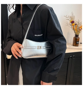 Close-up of metallic silver crescent shoulder bag with minimalist square buckle detail