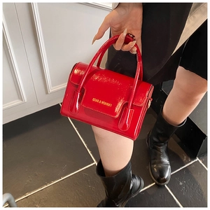 Detail of red patent leather mini handbag featuring dual handles and fashion slogan
