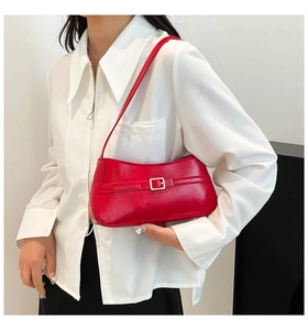 Detail of red faux leather shoulder bag with a gold metal square buckle and sleek strap