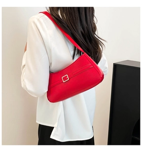 Detail of red leather shoulder bag showing the signature gold square buckle and texture