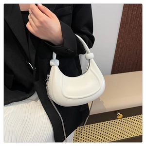 Detail of white crescent bag with knotted handle and elegant metal chain strap