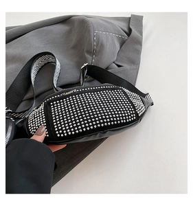Detail of black PU leather chest bag with silver rivets and striped canvas strap