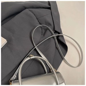 Close-up of textured silver handbag with golden hardware and adjustable strap