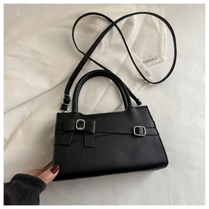 Détail du petit sac noir avec nœud papillon et boucle métallique argentée élégante