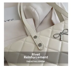 Detailed macro shot of reinforced silver rivets on a beige quilted leather tote bag