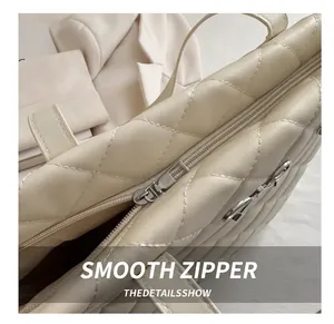 Close-up of smooth metal zipper and quilted leather texture on cream tote bag