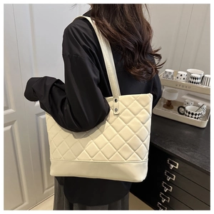 Detail of off-white quilted tote bag with diamond pattern and long shoulder straps
