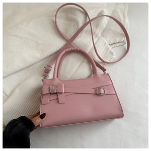 Détail du sac à main rose avec boucle métallique, nœud décoratif et bandoulière réglable