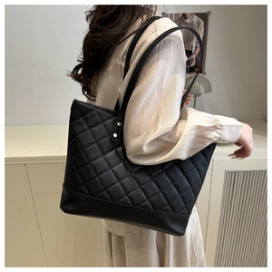 Close-up of black quilted tote bag showing fine diamond stitching and silver rivets