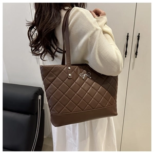 Detailed view of dark brown quilted tote bag with silver bow accent on shoulder