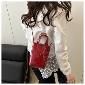 Détail du petit sac bandoulière rouge avec gravure Fashion et nœud décoratif