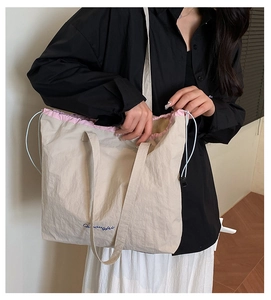 Vue détaillée du grand sac cabas crème avec cordons roses porté par un mannequin