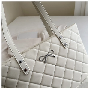 Detailed view of quilted tote bag with silver bow ornament and rivet strap accents