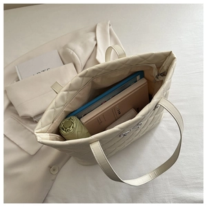 Macro shot showing large capacity interior of quilted tote bag with metal bow detail