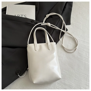Gros plan sur le sac de téléphone vertical blanc crème minimaliste avec nœuds sur costume