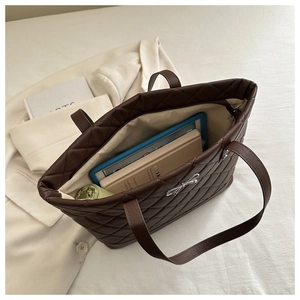 Detail of quilted brown tote bag showing spacious interior with tablet and books