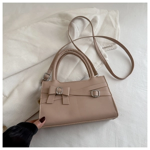 Détail du sac beige avec un nœud en cuir et une boucle métallique argentée