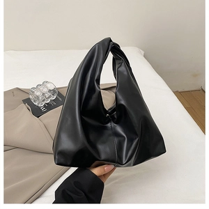 Detail of a black pleated dumpling bag featuring a soft leather texture and knotted handle