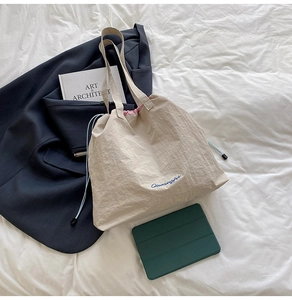 Détail du sac cabas à cordon avec doublure rose et broderie bleue sur toile blanche
