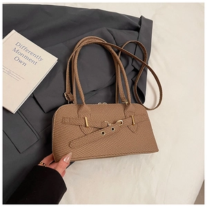 Detail of a brown woven shoulder bag featuring cross leather straps and gold metal hardware