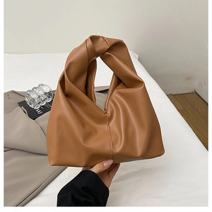 Detail of a brown ruched cloud bag featuring a unique knotted handle and soft leather texture