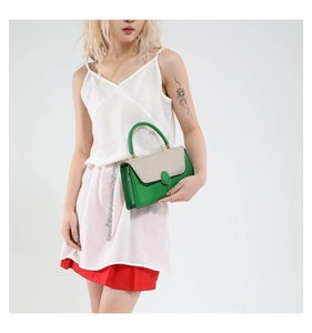 Close-up of stylish green leather bag with cream flap and green oval buckle detailing