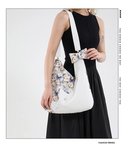 Detailed shot of floral print shoulder bag with bow charm and pearl accents on black dress