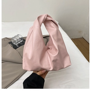 Detail of pink cloud handbag featuring unique knotted handle and soft leather texture
