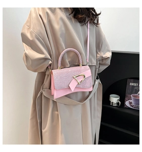 Detail of pink hourglass handbag with glitter flap and gold D-ring hardware on a trench coat