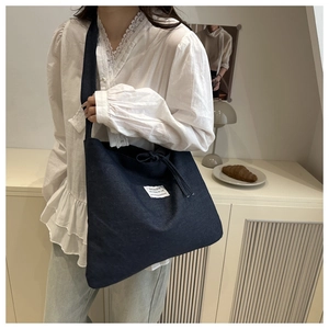 Deep blue denim tote bag with stylish white patch label and long shoulder straps